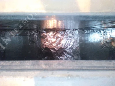 Obloge kamina - Intermont Zatvoreni prostor unutar obloge kamina u izgradnji. Izolacija od kamene vune obrubljena je sjajnom aluminijskom samoljepljivom trakom oko otvora (kanala) za cirkulaciju zraka radi osiguranja nepropusnosti i toplinske zaštite.